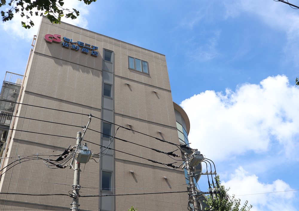 青空の下、「セレモニア 佐野商店」の看板を掲げた社屋
